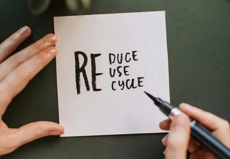 Hand writing the words "Reduce, Reuse, Recycle" on a piece of paper, emphasizing the importance of sustainability for development. As we all know it is a great principle for clean environment.